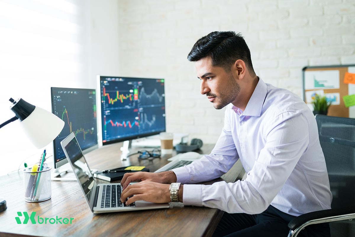 تریدر در حال انجام معامله با لپ تاپ